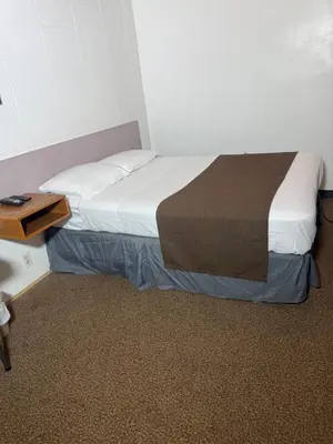 a bed in a small room with a wooden table at Sunrise Motel in Consort