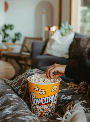 a person sitting on a couch with a cup of popcorn at First Light - Waterfront, Hot tub, Sauna, EV in Tofino