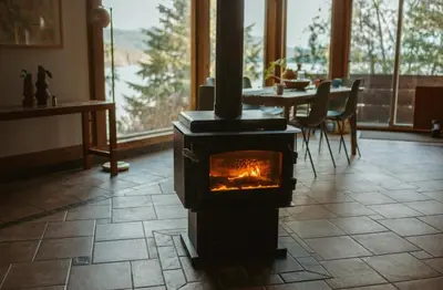 a stove in the middle of a room with a table at First Light - Waterfront, Hot tub, Sauna, EV in Tofino