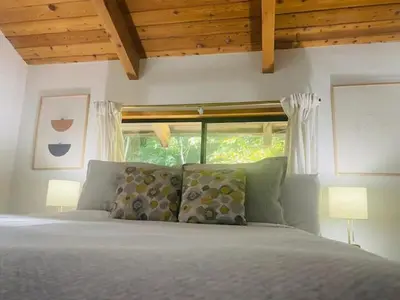 a bedroom with a bed with two lamps and a window at First Light - Waterfront, Hot tub, Sauna, EV in Tofino