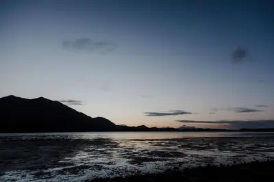 a sunset over a body of water with mountains at First Light - Waterfront, Hot tub, Sauna, EV in Tofino