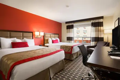 a hotel room with two beds and a desk at Ramada by Wyndham Edson in Edson