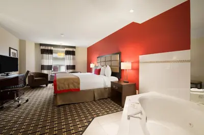 a hotel room with a bed and a bath tub at Ramada by Wyndham Edson in Edson