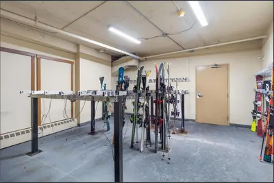 a room with a bunch of skis leaning against a wall at Main Village, Ski-in Ski-out, Hot Tub, Condo in Sun Peaks
