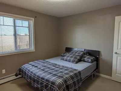 a bedroom with a bed with pillows and a window at Well located Condo in North of Calgary in Calgary