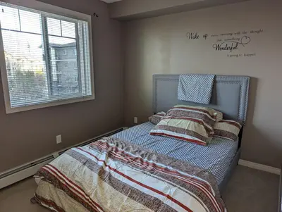 a bedroom with a bed with a blanket and a window at Well located Condo in North of Calgary in Calgary