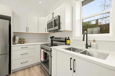 a kitchen with white cabinets and stainless steel appliances at Cozy Saanich Cottage ideal location to UVIC and Downtown in Victoria