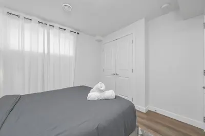 a white bedroom with a bed with a stuffed animal on it at Private Chic Orchard Getaway in Edmonton