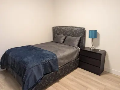 a bedroom with a bed and a nightstand with a blue lamp at Beautiful 2 Bedroom suite in White Rock
