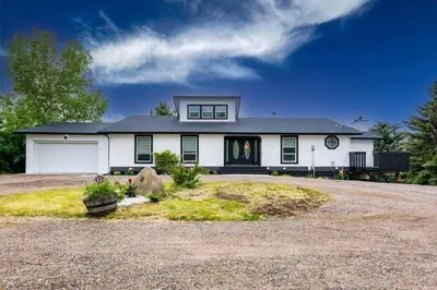 a large white house with a driveway at Walkout Bungalow with Pond Views in Balzac