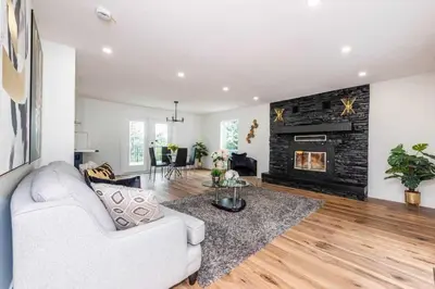 a living room with a white couch and a fireplace at Walkout Bungalow with Pond Views in Balzac