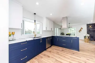 a large kitchen with blue cabinets and a wooden floor at Walkout Bungalow with Pond Views in Balzac