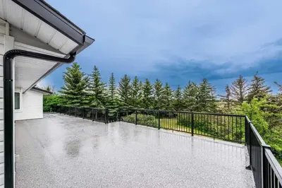 a balcony with a black fence and trees at Walkout Bungalow with Pond Views in Balzac