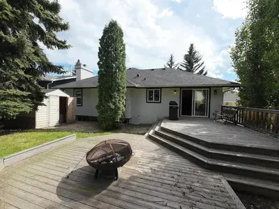 a house with a wooden deck with a bench on it at The Luxe Escape Calgary I 3BR Vacation Home in Calgary