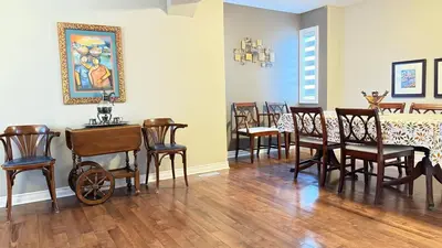 a dining room with wooden chairs and a table with a wheelchair at The Ridge Escape-3BR Deluxe Stay in Calgary