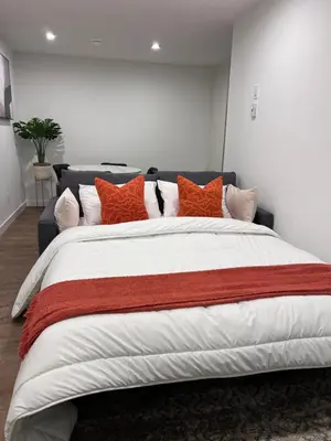 a bedroom with a large bed with orange pillows at Cozy home away from home in Calgary