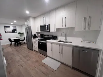 a kitchen with white cabinets and a sink and a table at Cozy home away from home in Calgary