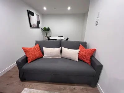 a gray couch with orange and white pillows on it at Cozy home away from home in Calgary