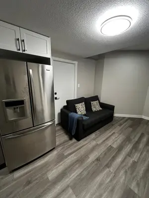a living room with a couch and a refrigerator at Entire 2 Ensuite Bedrooms in a Basement in Edmonton