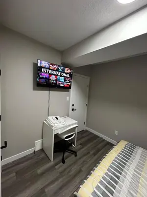 a bedroom with a desk and a tv on the wall at Entire 2 Ensuite Bedrooms in a Basement in Edmonton