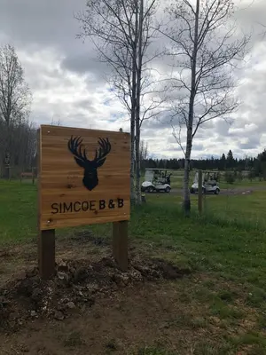a sign with a deer head on it in a field at Simcoe B&B - Incredible vacation suite in Smithers