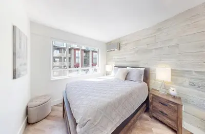 a bedroom with a bed and a wooden wall at Beautiful 1BR in Village Centre in Whistler