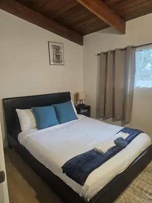a bedroom with a large bed with blue pillows at P&N Suites - Queen Room- DUBAI in Edmonton