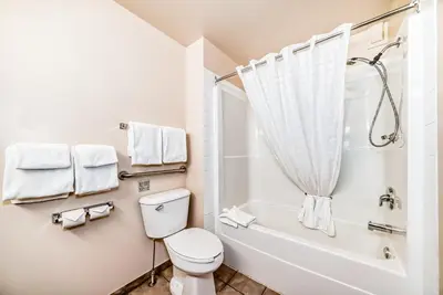 a bathroom with a toilet and a tub and a sink at Grande Cache Inn & Suites in Grande Cache
