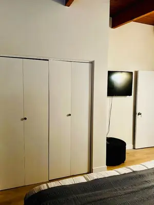 a bedroom with white cabinets and a tv on a wall at P&N Suites - DELUXE KING ROOM- PARIS in Edmonton