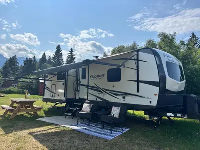 an rv parked in a field with a picnic table at Luxury Rocky Mountain Glamping in Golden Canada Family Friendly AC Campfire Northern Lights Stargazing in Golden