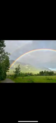 a rainbow in the sky over a green field at Luxury Rocky Mountain Glamping in Golden Canada Family Friendly AC Campfire Northern Lights Stargazing in Golden
