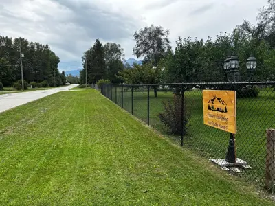 a fence with a sign on it next to a road at Luxury Rocky Mountain Glamping in Golden Canada Family Friendly AC Campfire Northern Lights Stargazing in Golden