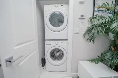 a washer and dryer in a white laundry room at Entire 1 bed and Den Near YEG International Airport in Nisku
