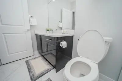 a white bathroom with a toilet and a sink at Entire 1 bed and Den Near YEG International Airport in Nisku