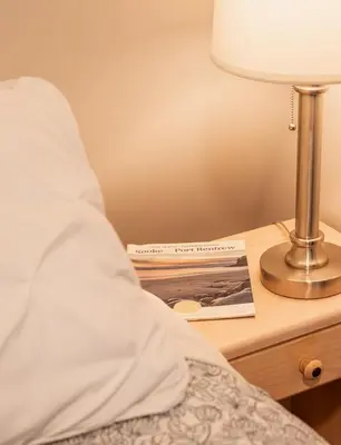 a bedside table with a lamp and a book on it at Quiet and rural apartment in the country in Cobble Hill