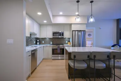 a kitchen with white cabinets and a island with bar stools at 2 bedrooms-3 beds 2 baths-Rocky Creekside Retreat - Top Floor - Heated Pool and Hot Tub in Dead Man's Flats
