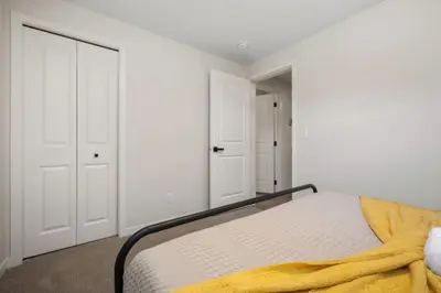 a bedroom with a bed with a yellow blanket on it at Private Lower Suite, Sleeps 4, Queen Bed, Netflix, Parking in Balzac