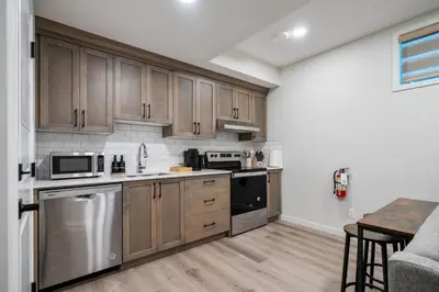 a kitchen with stainless steel appliances and wooden cabinets at Private Lower Suite, Sleeps 4, Queen Bed, Netflix, Parking in Balzac