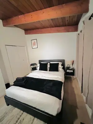 a bedroom with a large bed with white sheets and black pillows at P and N Suites in Edmonton
