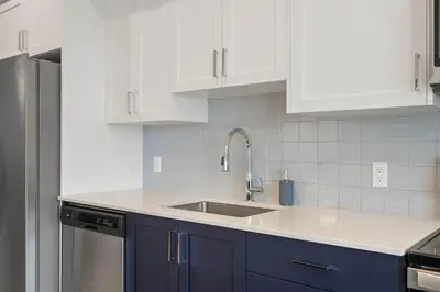 a kitchen with white cabinets and a sink at Skyline Retreat Spacious 4BR Home with Balcony! in Calgary