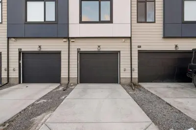 a building with four garage doors on it at Skyline Retreat Spacious 4BR Home with Balcony! in Calgary