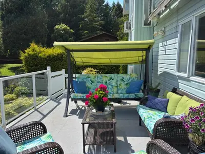 a patio with couches and a yellow umbrella at Bayview Bed and Breakfast in Mill Bay