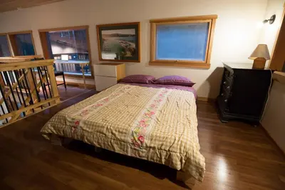 a bedroom with a bed and a staircase at Jordan River Coastal Cottage in Shirley