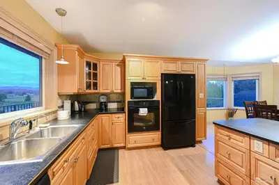 a kitchen with wooden cabinets and a black refrigerator at Fort Wine Burrow, Entire Private Estate Home in Maple Ridge District Municipality