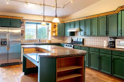 a kitchen with green cabinets and a large island at Fort Wine Manor, Entire Private Estate Home in Maple Ridge District Municipality