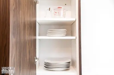 a cupboard with plates and a stack of plates at Park Life Escape-King Beds-Sleeps 10-Pet Friendly in Edmonton