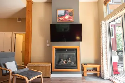 a living room with a fireplace with a flat screen tv at Surfers' Nest - Waterfront home in Ucluelet in Ucluelet