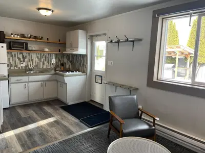 a kitchen with white cabinets and a chair and a window at Pinewood Inn in Golden