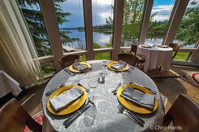 a dining room with a table with a view of the water at Eagle's Nest Resort in Anahim Lake