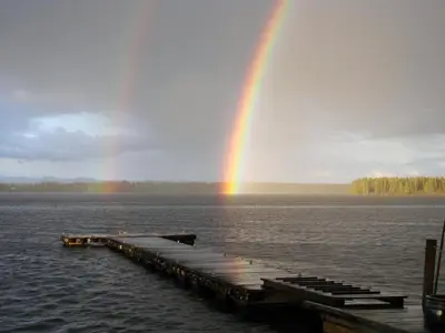 a rainbow over a dock in the water with a wooden pier at Eagle's Nest Resort in Anahim Lake